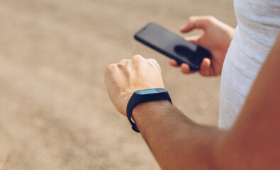 Photo of man hands touching phone and setting configuration generic design smart watch.