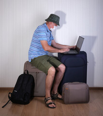 a man in a medical mask works on a laptop on suitcases