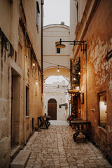 Schmale Gasse mit Lichterkette und Tischen in der Altstadt von Matera in Italien 