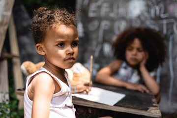 selective focus of poor african american child near curly sister