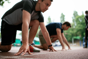 Athlete men in sportswear in start position for running. Close up..