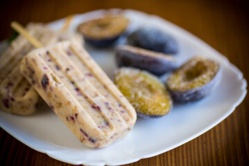 plum sweet homemade ice cream on a stick with slices of plum inside, in a plate