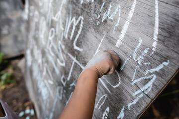 cropped view of african american child writing on chalkboard