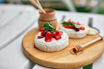 Grilled camembert cheese with strawberry, honey and basil leaves, delicatessen, camembert cheese fondue on white background..