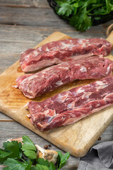 Fototapeta premium Lamb meat. A young lamb on a wooden Board on a gray wooden kitchen table. Lamb meat and cooking ingredients. The view from the top 