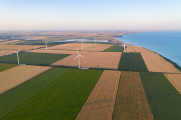 Sunset over the windmills. Wind turbines over fields of wheat and sunflowers