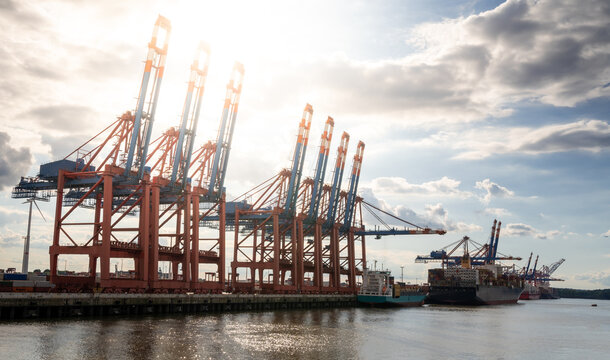 Sun beams through cranes at the harbor of Hamburg, Germany.