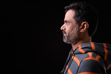 Portrait of mature bearded Indian man with curly hair wearing hoodie