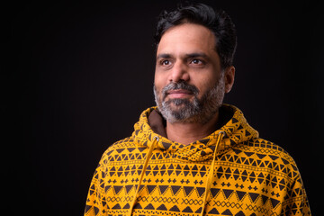 Fototapeta premium Portrait of mature bearded Indian man with curly hair wearing hoodie