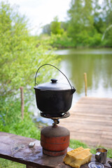 Cooking rice using a cast iron boiler in nature. Camping, food is prepared in nature on a gas boiler. Outdoor recreation.