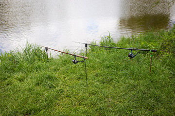 Fishing, fishing rods are on stands on the shore of the pond. Outdoor recreation, summer, vacation, day off.