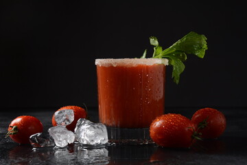Glass of fresh tomato juice and tomatoes on Dark background with water drops