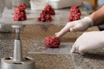 
preparation of homemade hamburgers with ground meat and hands making them on kitchen counter