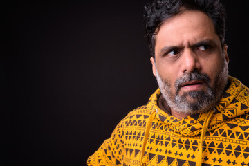 Portrait of mature bearded Indian man with curly hair wearing hoodie