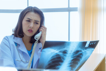 Portrait female doctor looking at x-ray image consulting on phone by detail in film with analysis...
