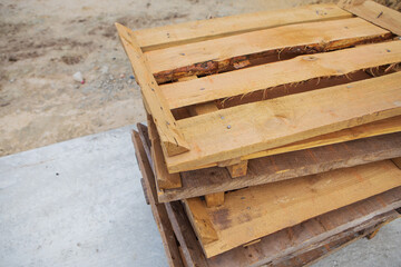 A lot of old wooden pallets stand on the street on top of each other, all for repair.