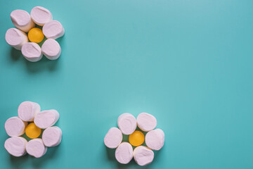 Fototapeta na wymiar food design. Chamomile with marshmallows and candy against a blue background. Edible flowers