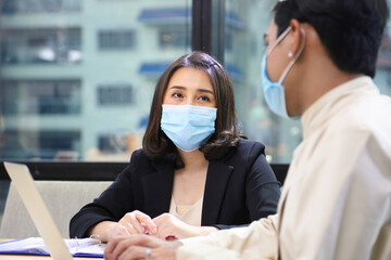Business women in formal wear with protective facial mask discussing with colleague in business...