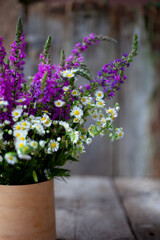 A bouquet of wild flowers. Summer wild flower. Wooden background and table. Place for text. Small-petal one-year lat. Er geron nnuus, Phalacrol ma nnuum and Veronica spicata. Copy space.