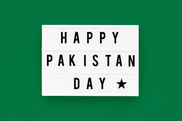 HAPPY PAKISTAN DAY written in a lightbox on a green background. Independence day date. Top view