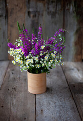 A bouquet of wild flowers. Summer wild flower. Wooden background and table. Place for text. Small-petal one-year lat. Er geron nnuus, Phalacrol ma nnuum and Veronica spicata. Copy space.