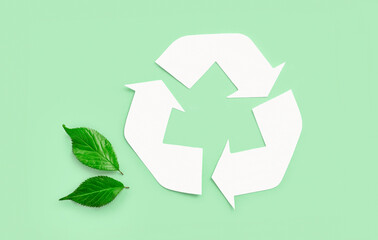 Recycle eco icon with green leaves on light green background. Top view.