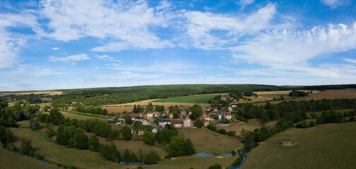 Fototapeta na wymiar Panorama sur un village traditionnel et une petite rivière, à Beurvon, vers Nevers, dans la Nièvre, en Bourgogne, en France et en été.