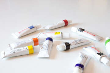 Tubos de pintura de acuarela de distintos colores sobre una mesa blanca