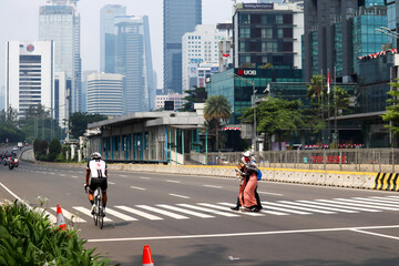 A cyclist who is enjoying the empty streets of Jakarta in the new normal era with an office building background