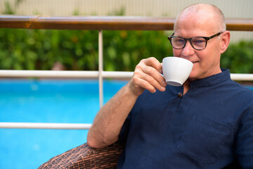 Happy senior handsome tourist man drinking coffee and relaxing with nature outdoors