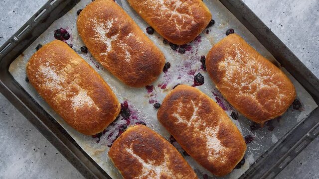 Delicious hot homemade buns stuffed with blueberry on a baking tray