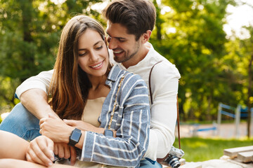 Fototapeta premium Image of caucasian couple smiling and hugging while walking in park