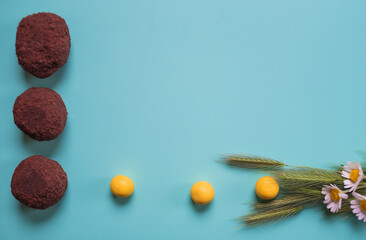 Three round chocolate cakes, fresh small chamomile and yellow candy. Beautiful blue background with sweets