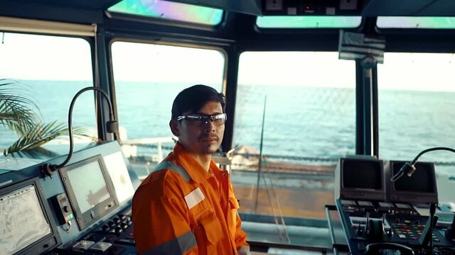 Filipino deck Officer on bridge of vessel or ship wearing coverall during navigaton watch at sea