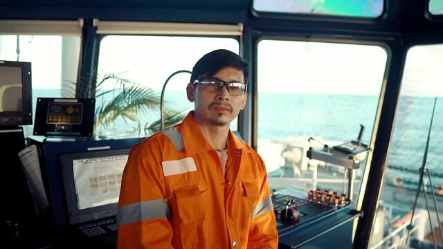 Filipino deck Officer on bridge of vessel or ship wearing coverall during navigaton watch at sea