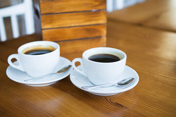 Two cups of coffee on a wooden table, a place for text.