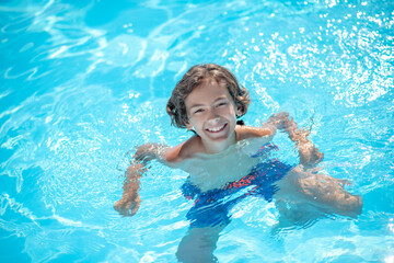 Fototapeta na wymiar Tanned boy shoulder-length in swimming pool water