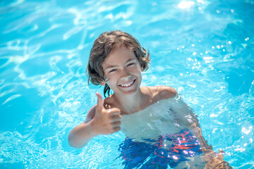 Boy in water showing gesture everything is fine