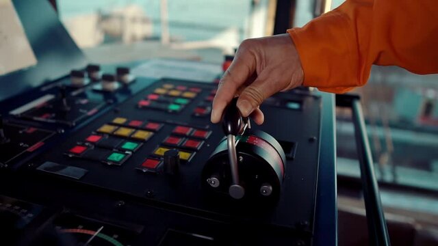 Filipino deck Officer on bridge of vessel or ship wearing coverall during navigaton watch at sea . He is maneuvering with cpp thrusters propulsion