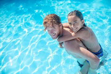 Dad with son on his back walking in water