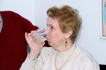 Close-up aged lady that is drinking from the glass.