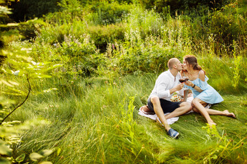 Naklejka na ściany i meble Tender beautiful couple kissing, having a picnic at the park