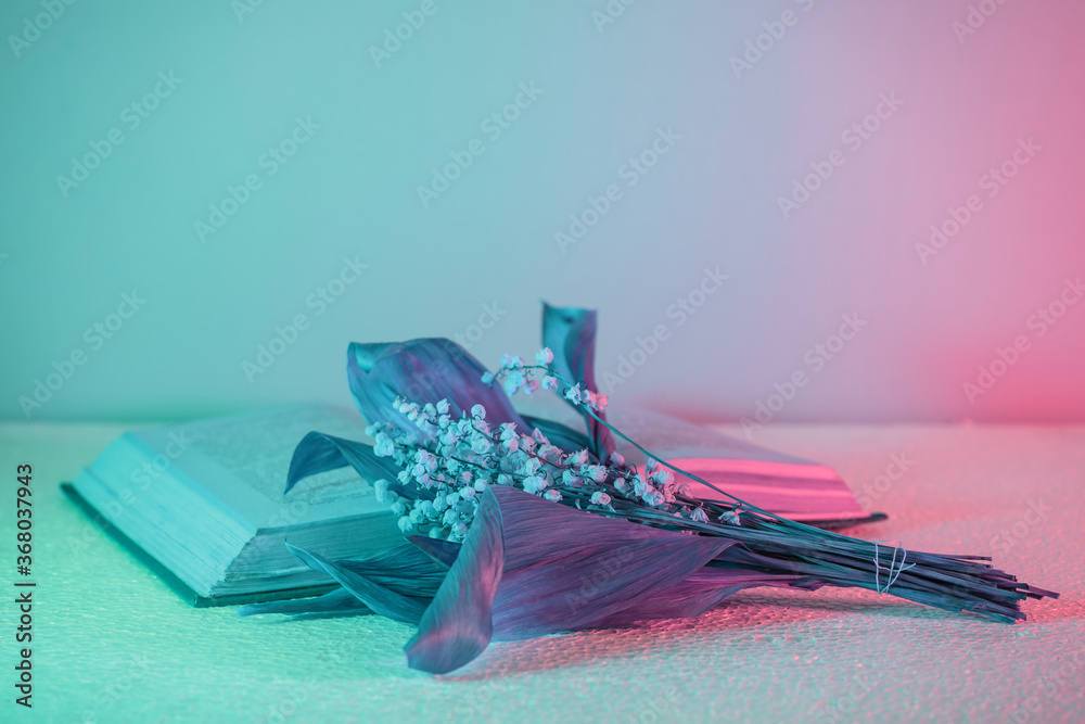 Poster Close up Beautiful open book and flowers  in neon light. Minimalism retro style concept. 80s. Background pattern for design.