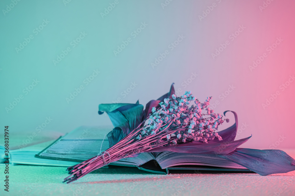 Aufkleber Close up Beautiful open book and flowers  in neon light. Minimalism retro style concept. 80s. Background pattern for design.