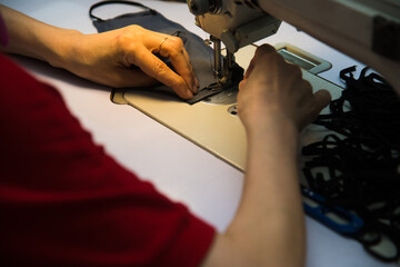 Woman hands with fabric at sewing machine