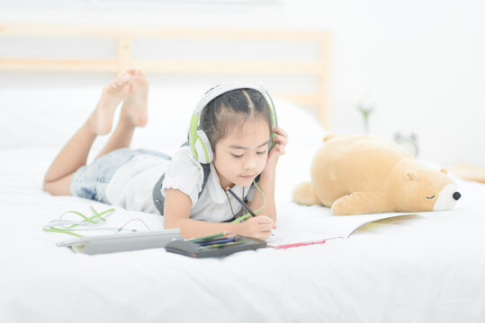 Cute Asian Little Girl Doing Homework,writing With Colourful Pencils On Bed At Home. Elegant Design For Kid Playing, Preschool Learning And Creative Art Education Concept.