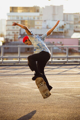Skateboarder doing a trick at the city's street in summer's sunshine. Young man in sneakers and cap...
