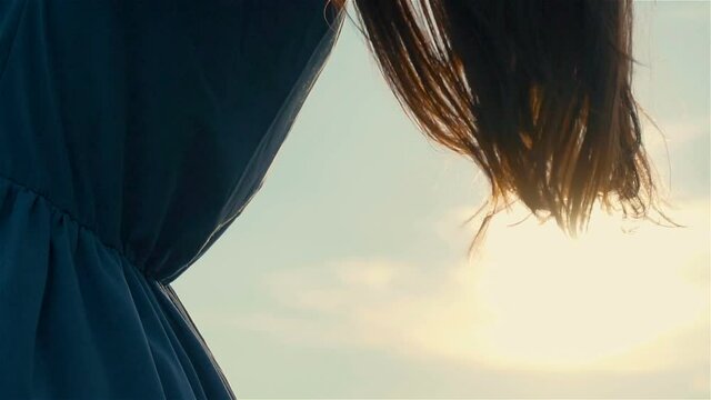Close back view of woman black hair tender movement in air in slow motion at sunset. Happy and successful lifestyle concept