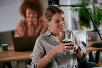  Young businesswoman drinking coffee in her office. Beautiful businesswoman enjoying in the mornings.