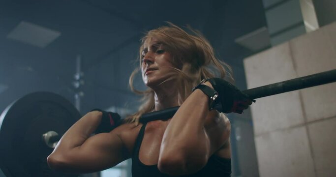 the woman athlete trains in the gym, raises the bar. Strength is power. Muscular female shirtless athlete doing deadlift exercise at the gym.